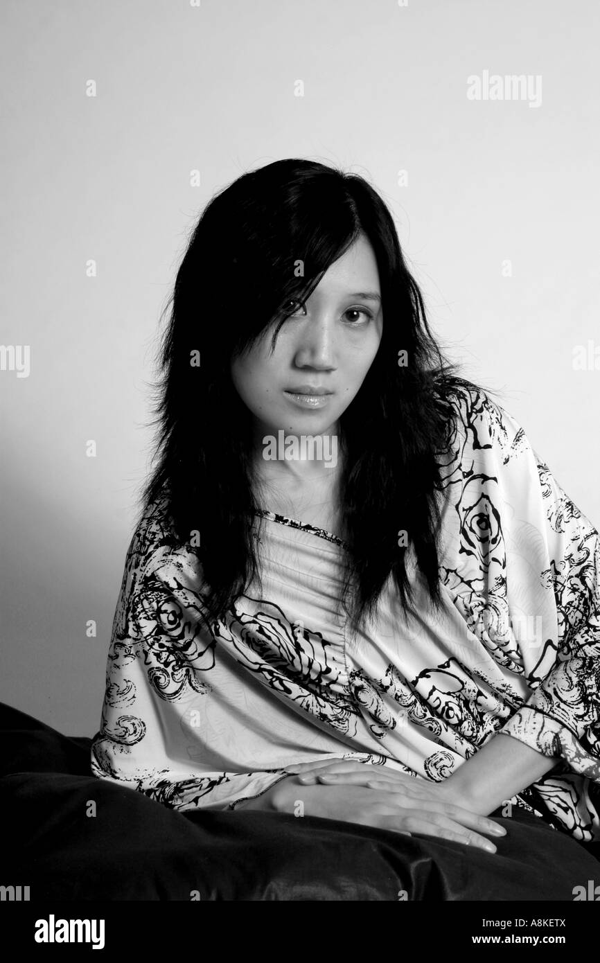 Noir et blanc de belle femme asiatique en appui sur son coude avec un contact visuel avec la caméra. Banque D'Images