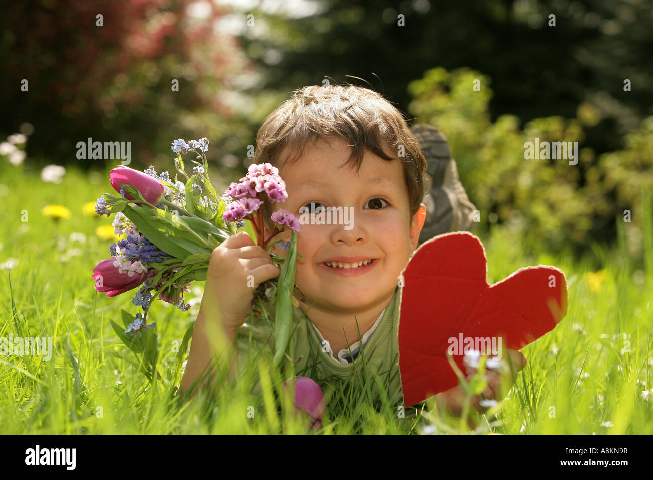 Un enfant tenant un cœur et un bouquet de fleurs Banque D'Images