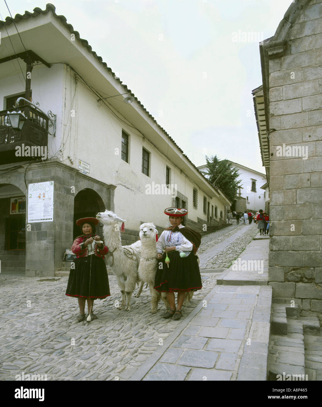 Cuzco Pérou femmes dans inca typique robe et de tourner avec des Lamas damées dans une rue pavée de prestations de touristes Banque D'Images