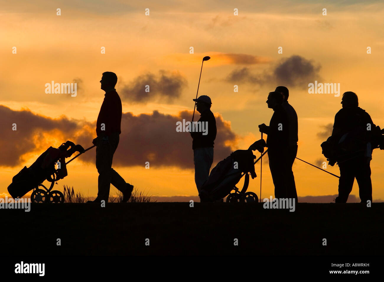 Le dernier trou de la journée. Cinq golfeurs se tenir sur le dernier té sur le soleil couchant. Banque D'Images
