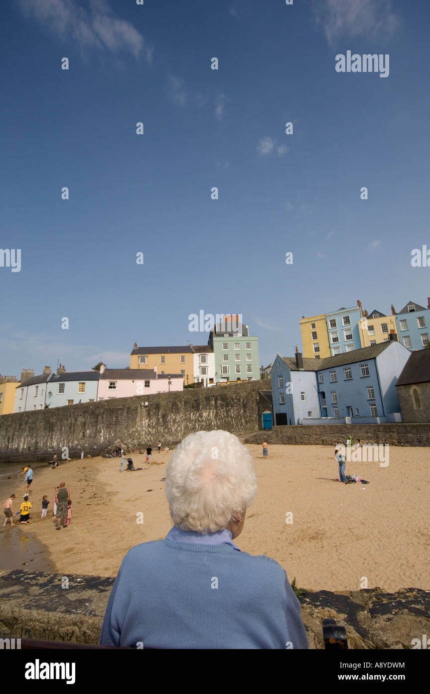 Le Pays de Galles à Cardiff - vue arrière d'une vieille femme aux cheveux gris assis par elle-même à elle seule au monde sur la plage UK Banque D'Images