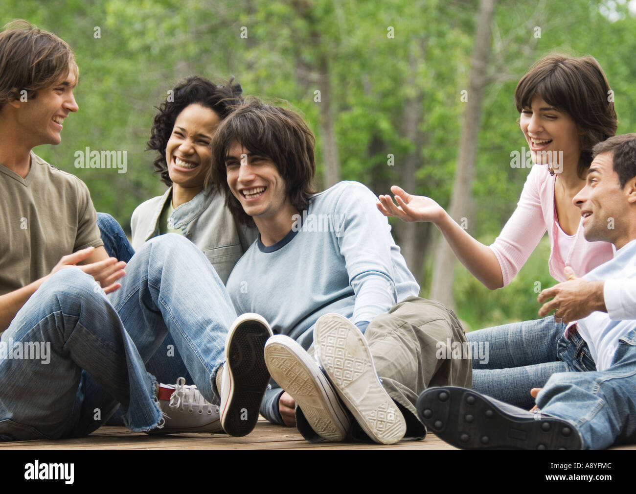 Groupe de jeunes amis assis autour de concert en plein air, rire Banque D'Images