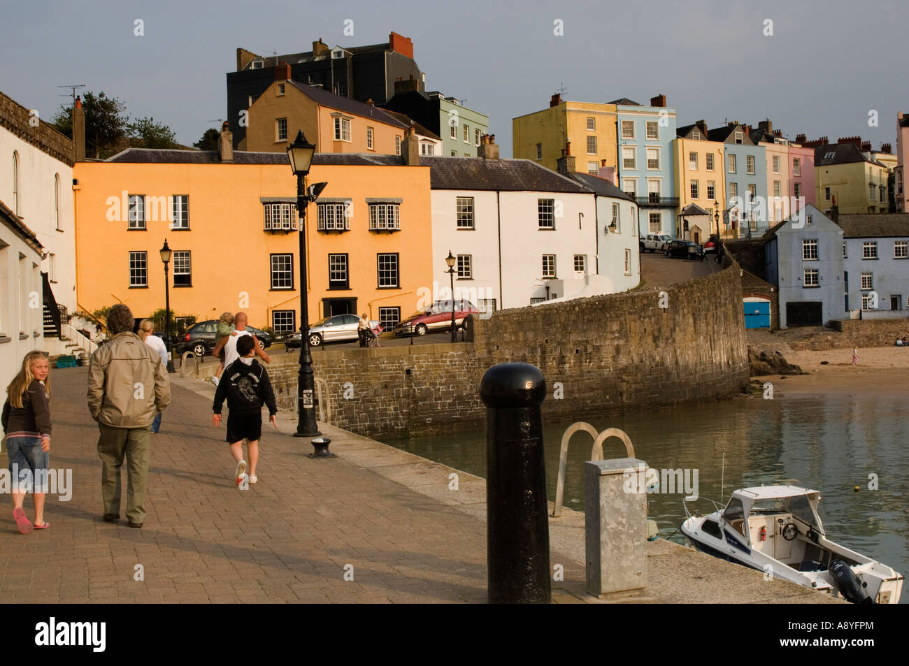 Les gens qui marchent sur les quais du port et plage du nord à marée haute Tenby Wales UK Banque D'Images