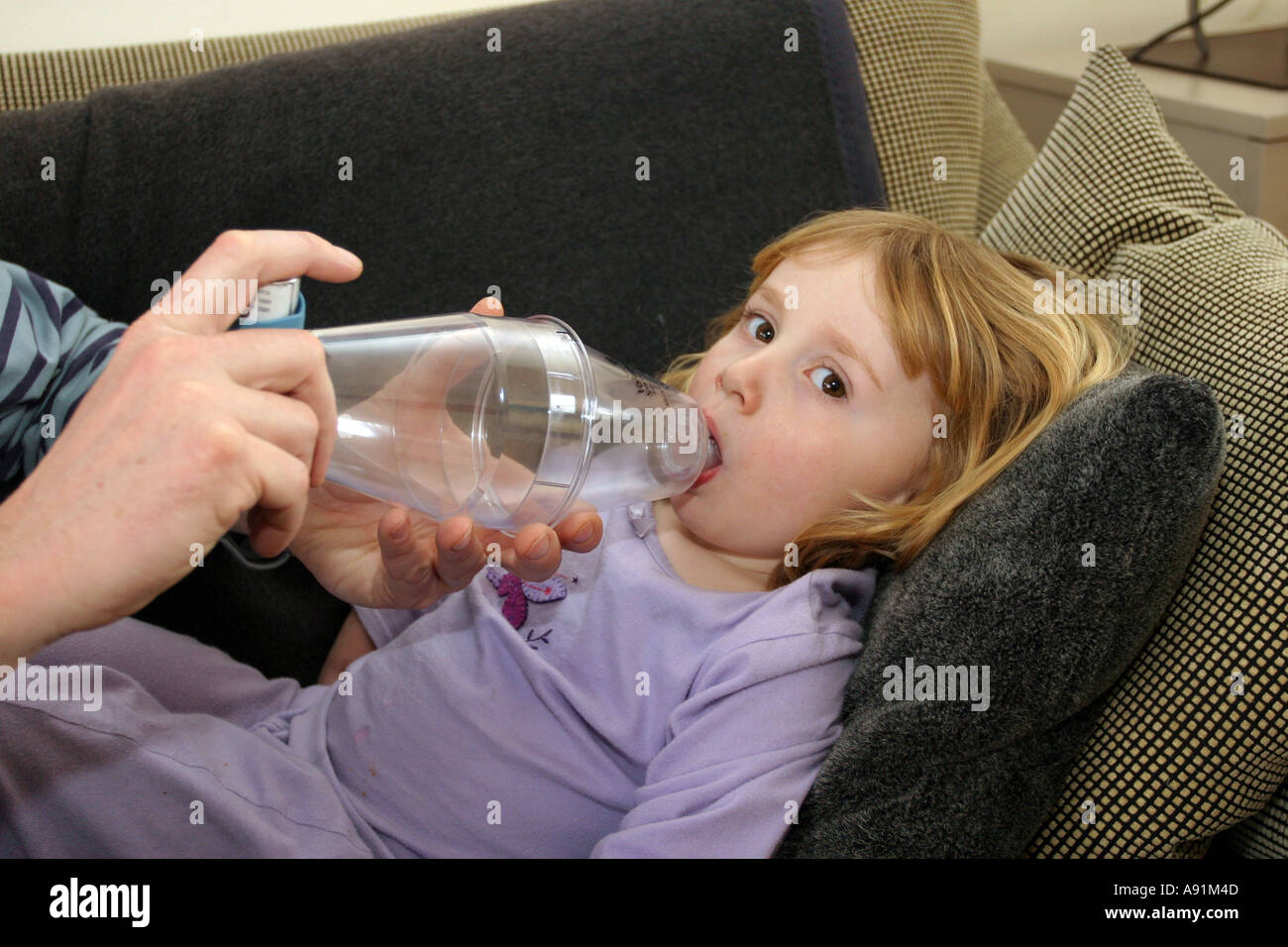 Père fille aidant à utiliser une entretoise en plastique de l'asthme (chambre) attaché avec un inhalateur à la suite d'une attaque. Banque D'Images