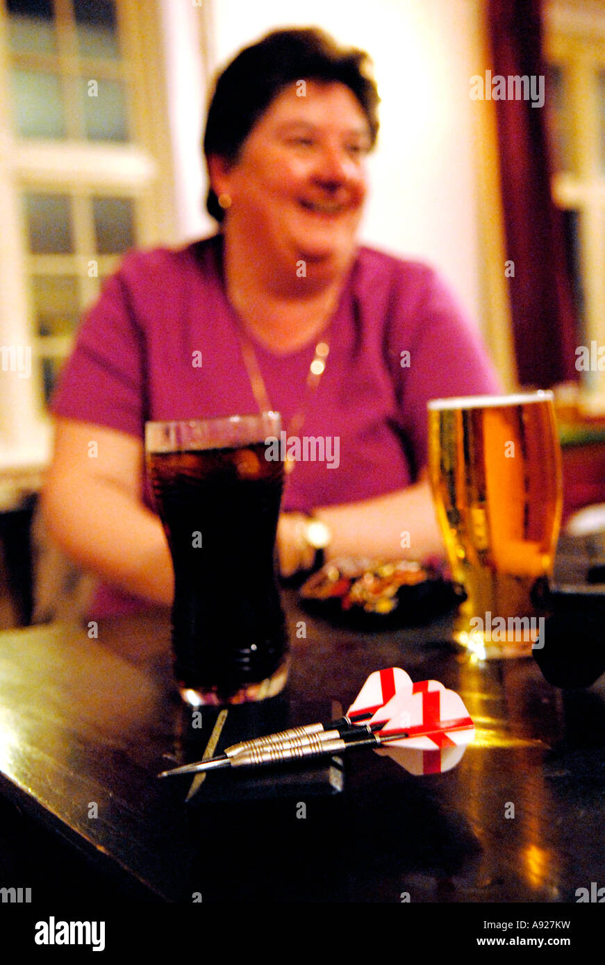 Une femme se détend avec de la bière tout en jouant aux fléchettes. Banque D'Images