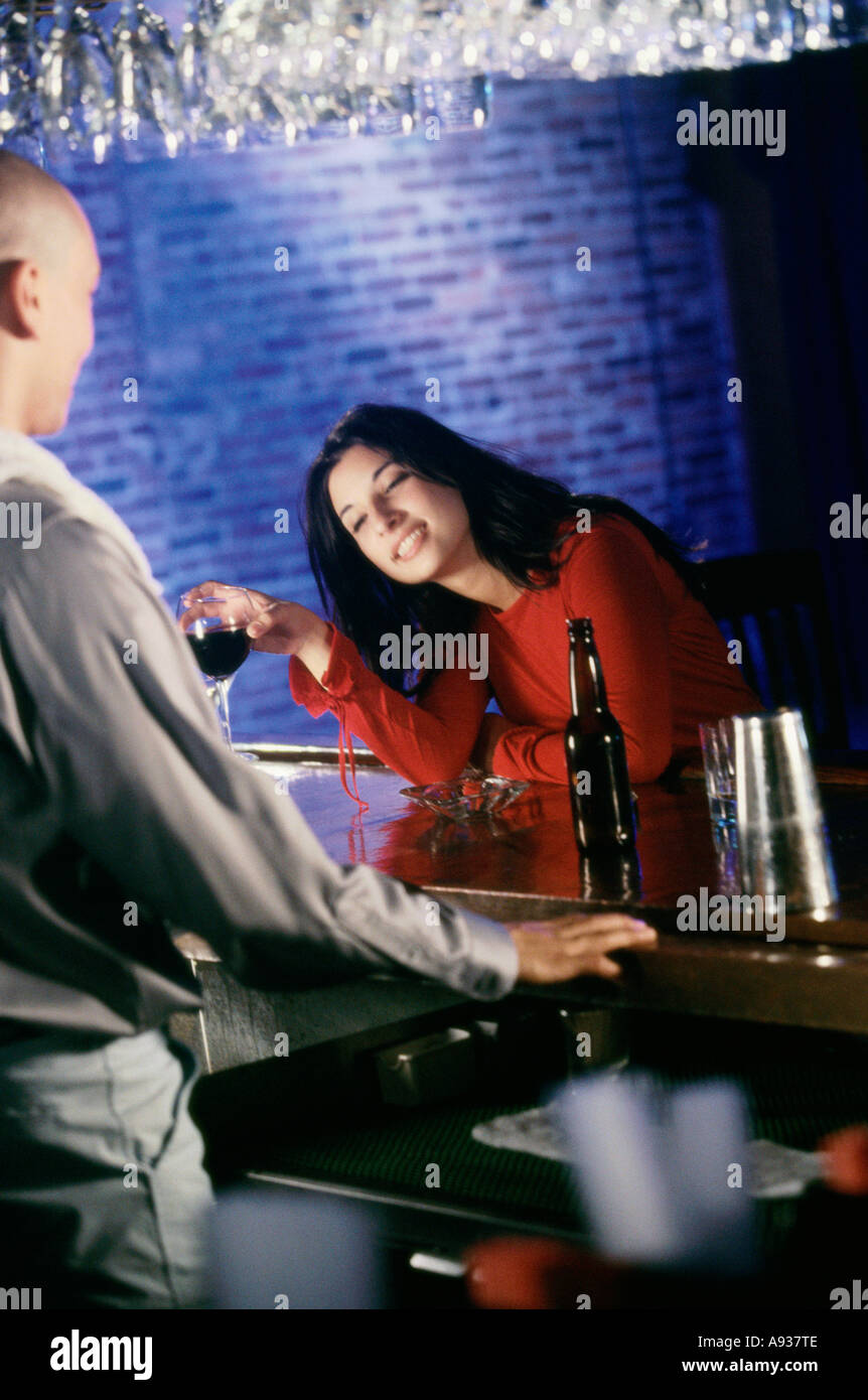 Jeune femme assise dans un bar tenant un verre de vin Banque D'Images