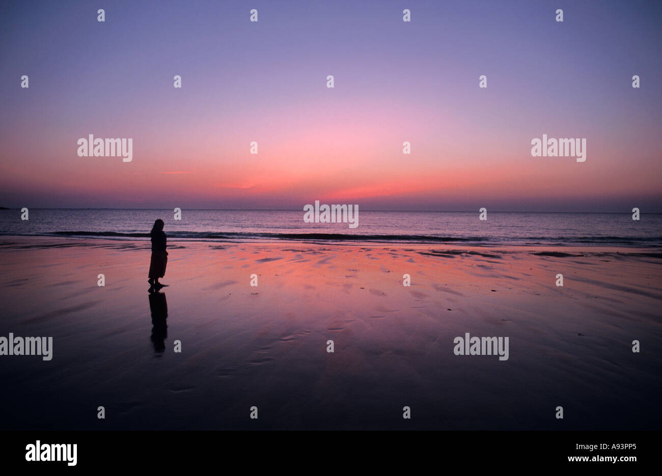 Woman standing on beach at sunset Bretagne France Europe Banque D'Images