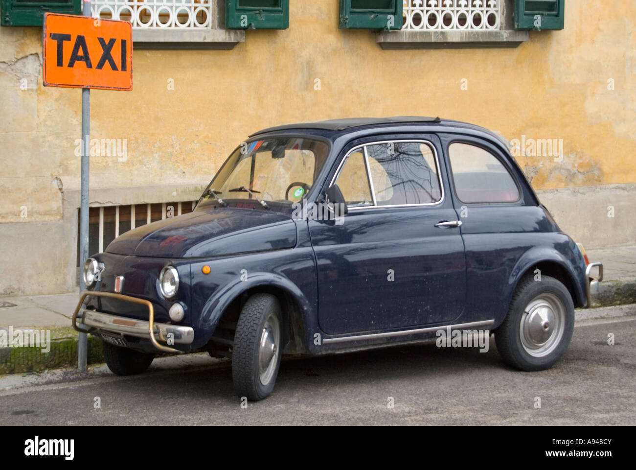 Horizontal comique close up of a classic Fiat 500 stationnée sur la route près d'une enseigne Banque D'Images