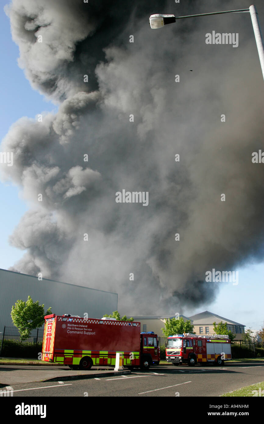 Le service d'incendie de véhicule de commande verticale sous panache de fumée et de débris qui tombent à l'incendie à l'entrepôt médical coleraine Banque D'Images