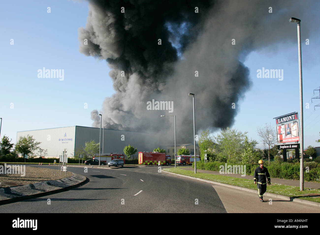 Le pompier s'éloigne de l'immense panache de fumée sur le feu à l'entrepôt médical coleraine Banque D'Images