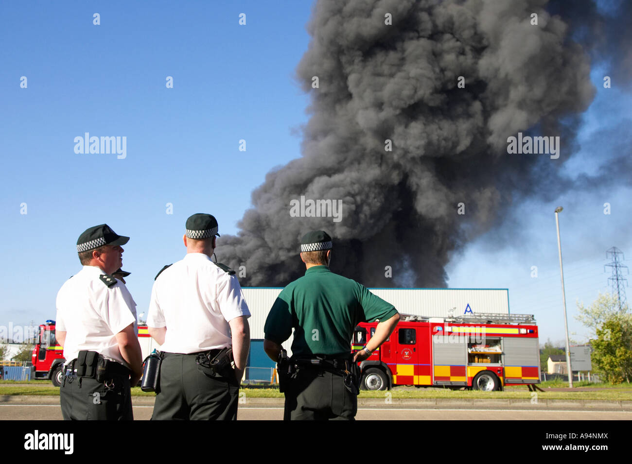 Agents psni regardant colonne de fumée s'élevant au-dessus de feu à l'entrepôt médical coleraine Banque D'Images