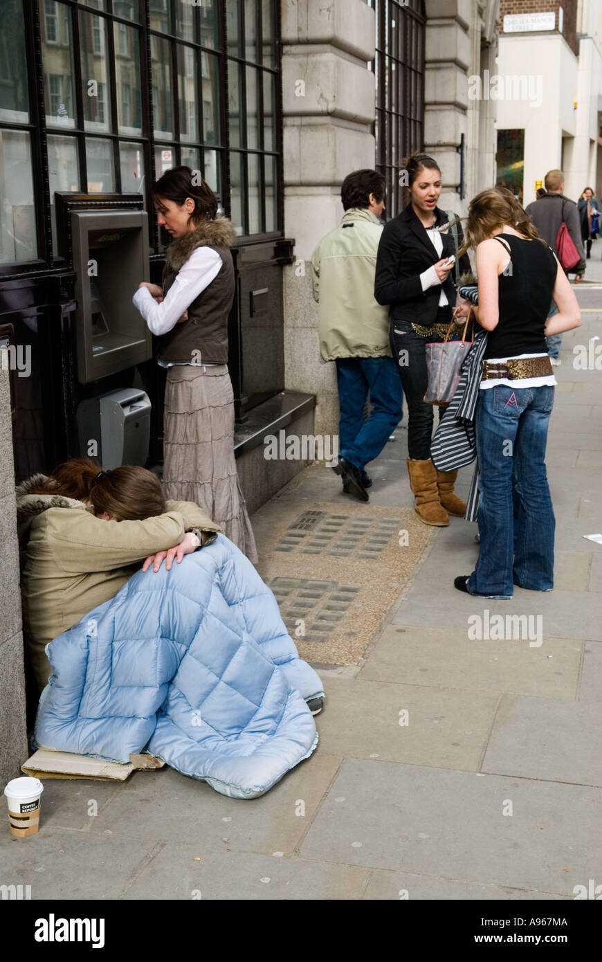 Les classes sociales pauvres riches contraste UK 2000s mendiant assis endormi à côté d'un point de trésorerie. Chelsea King Road, London SW3, en Angleterre. HOMER SYKES Banque D'Images