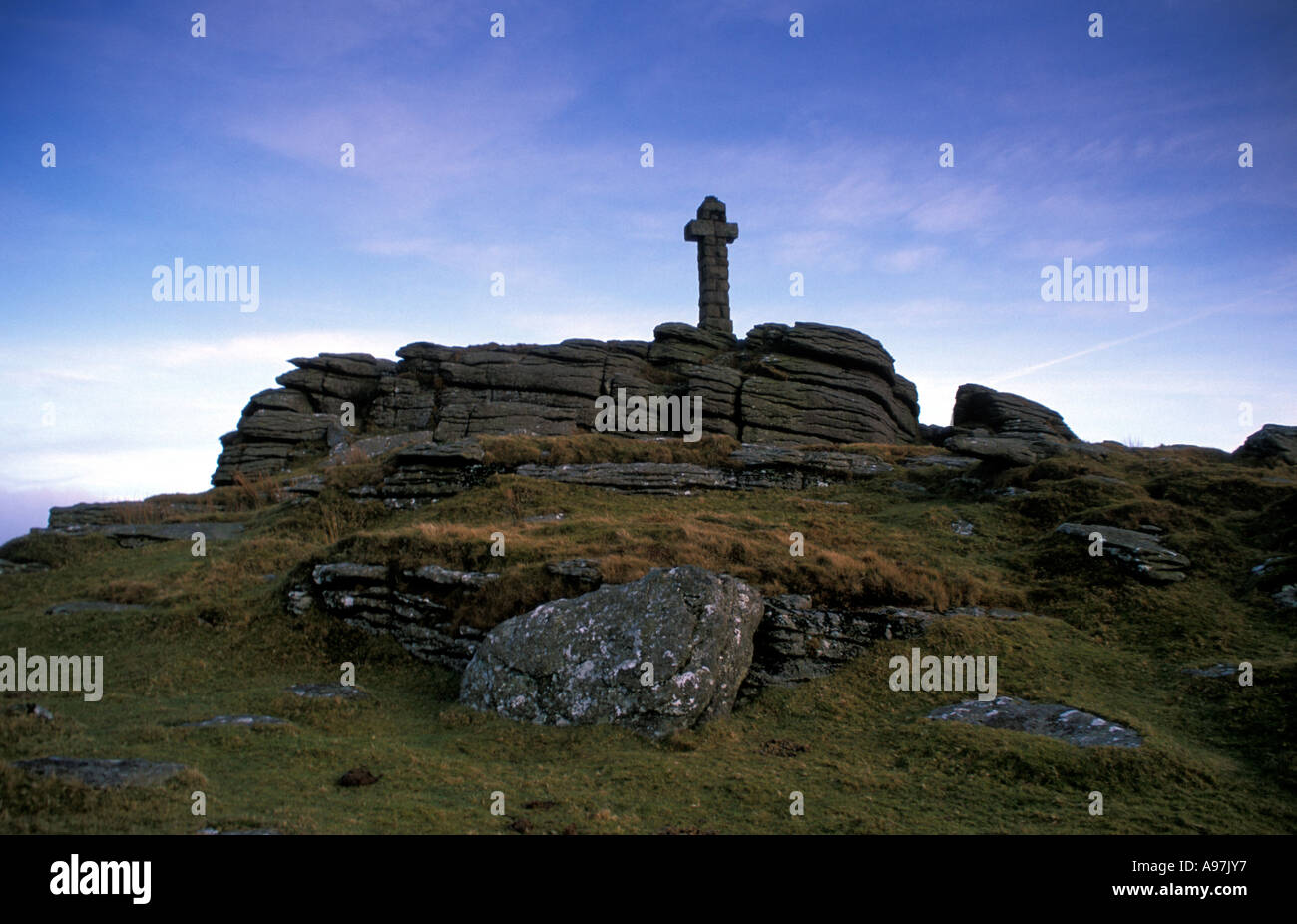 Un trait distinctif de l'affleurement de granit avec une croix de pierre debout fier contre ciel bleu Dartmoor National Park Banque D'Images