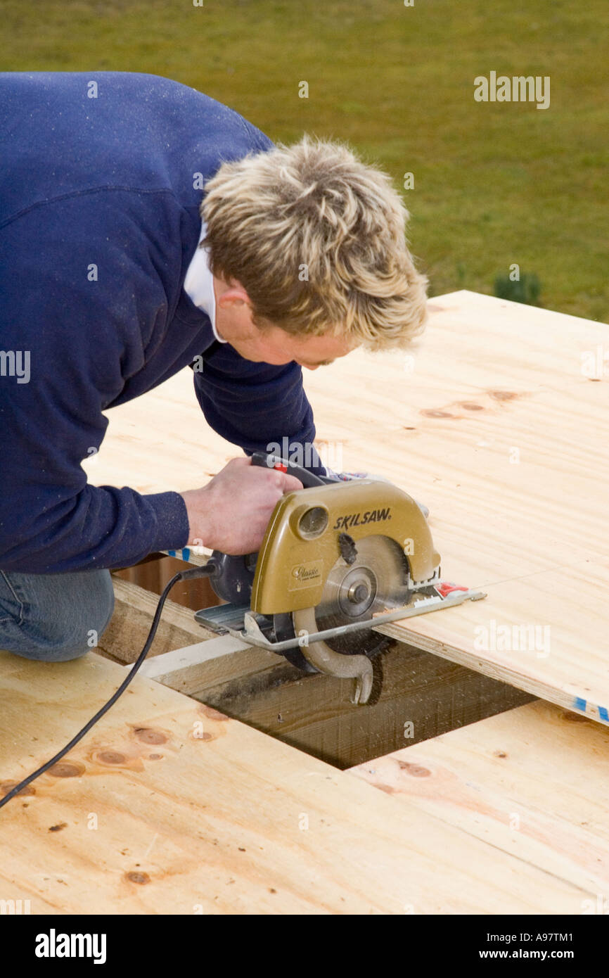 Un menuisier à l'aide d'une scie électrique pour couper une feuille de bois  pour la construction d'un toit Photo Stock - Alamy