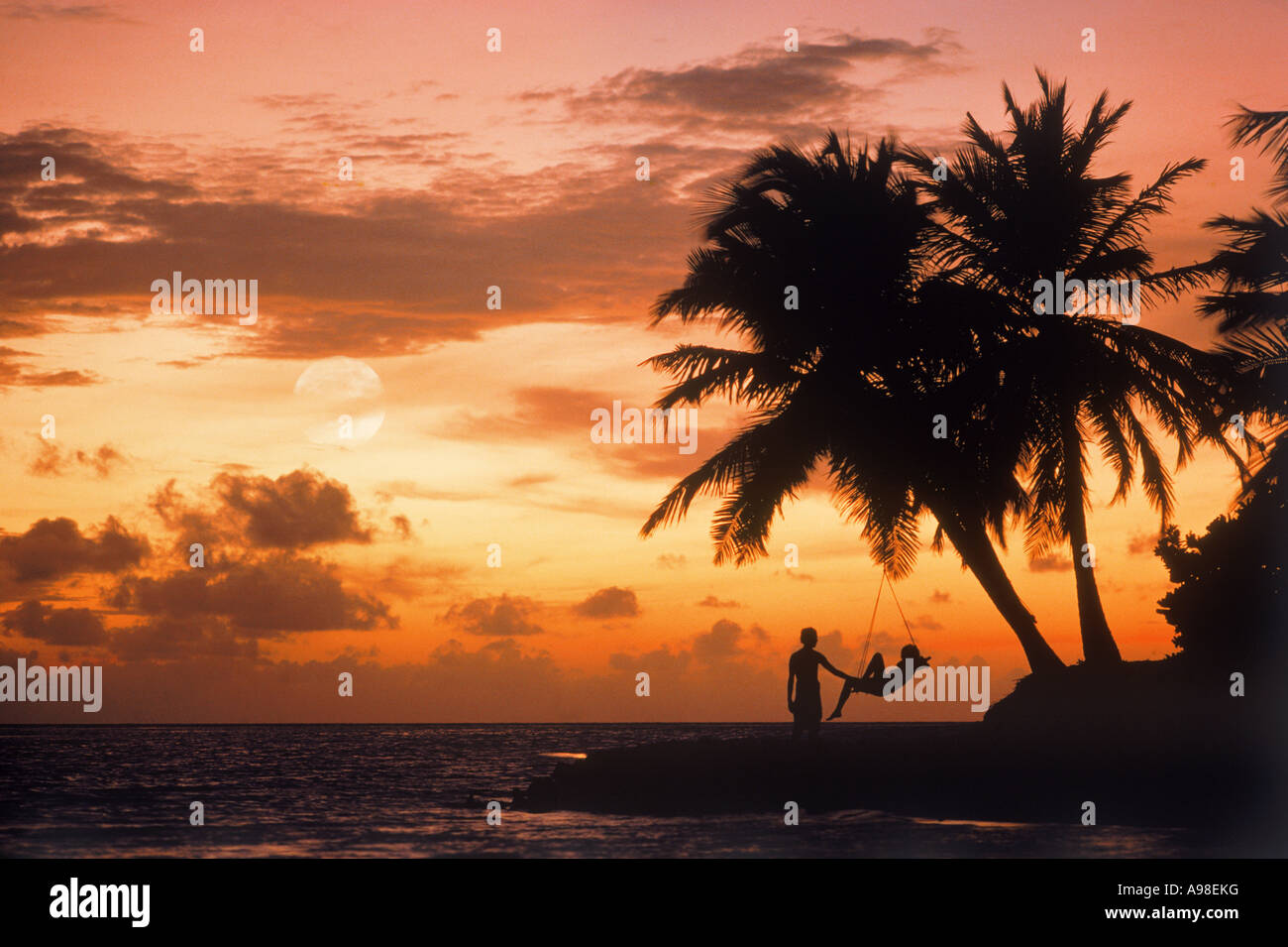 Couple on shore avec pleine lune au coucher du soleil sur l'île de Maayafushi dans les Maldives Banque D'Images