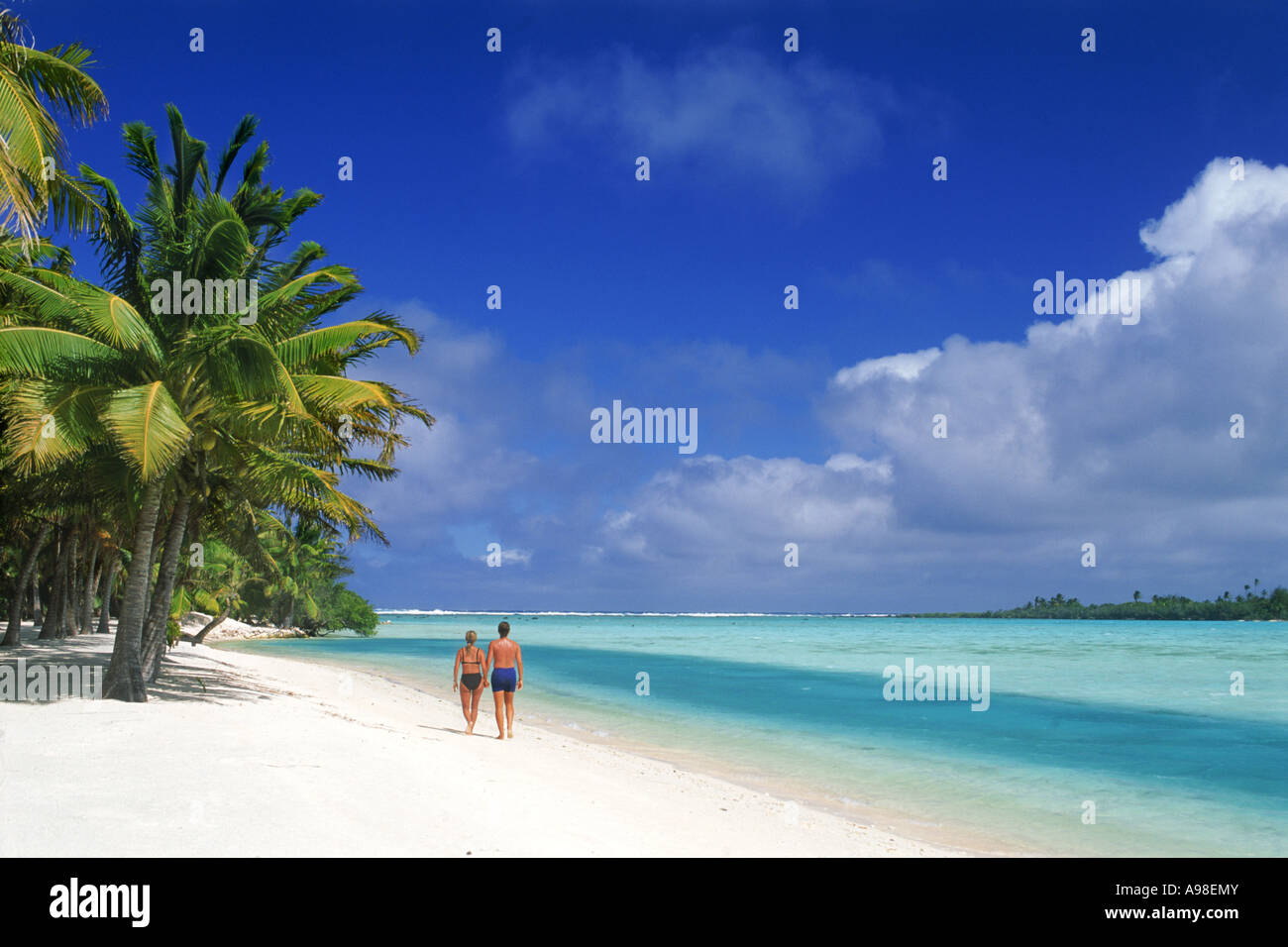 Couple walking along sandy shore sur l'île d'Aitutaki aux Îles Cook dans le Pacifique Sud Banque D'Images