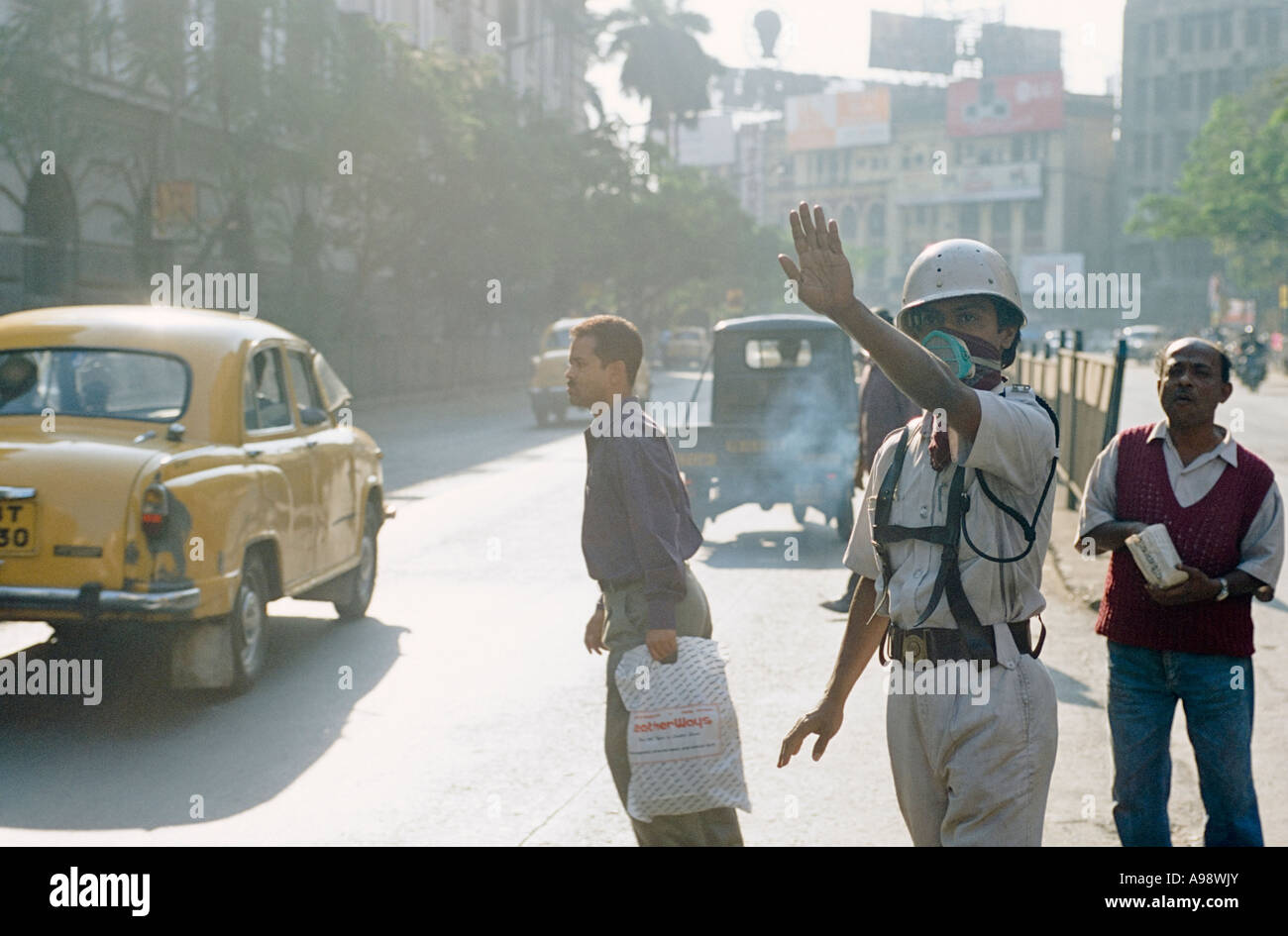 Au milieu de la pollution : la circulation en masque aide à traverser les navetteurs Calcutta (Kolkata) Street. L'Inde. Banque D'Images
