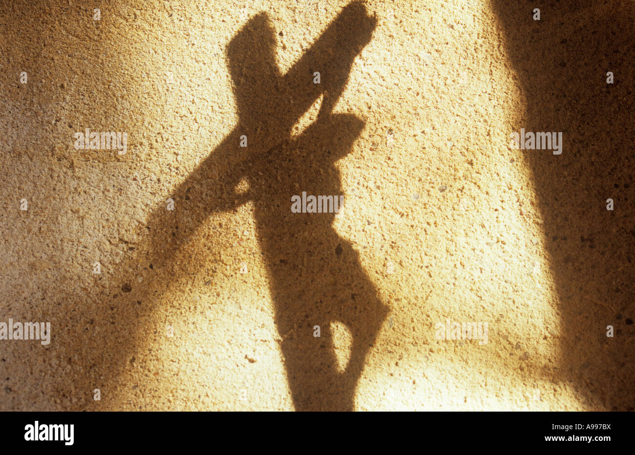Ombre contre un mur de rendu pâle Jésus Christ suspendu à un crucifix avec empiéter ombre de pilier Banque D'Images