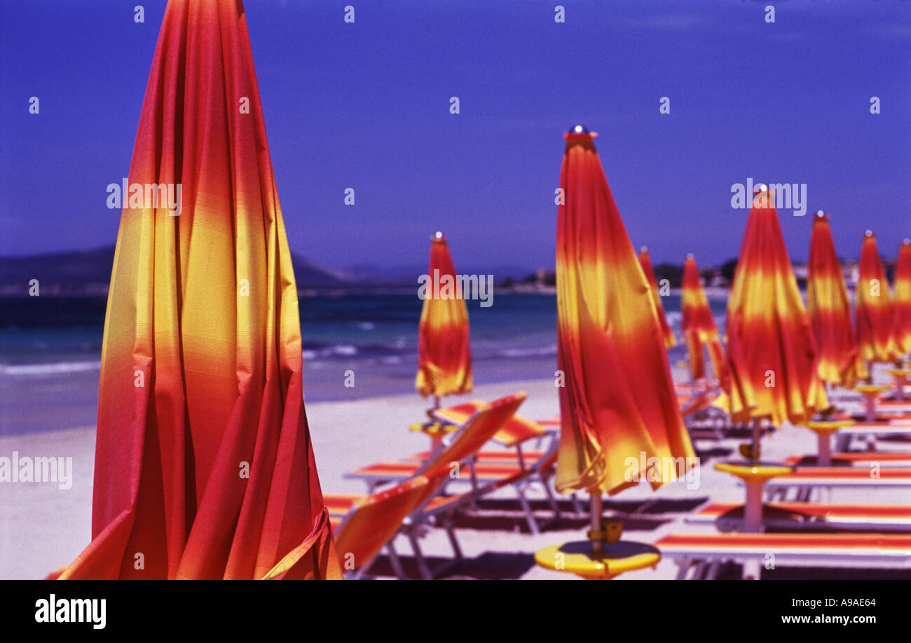 Le rouge et jaune de parasols et de chaises longues sur une jolie plage Alghero Sardaigne Banque D'Images