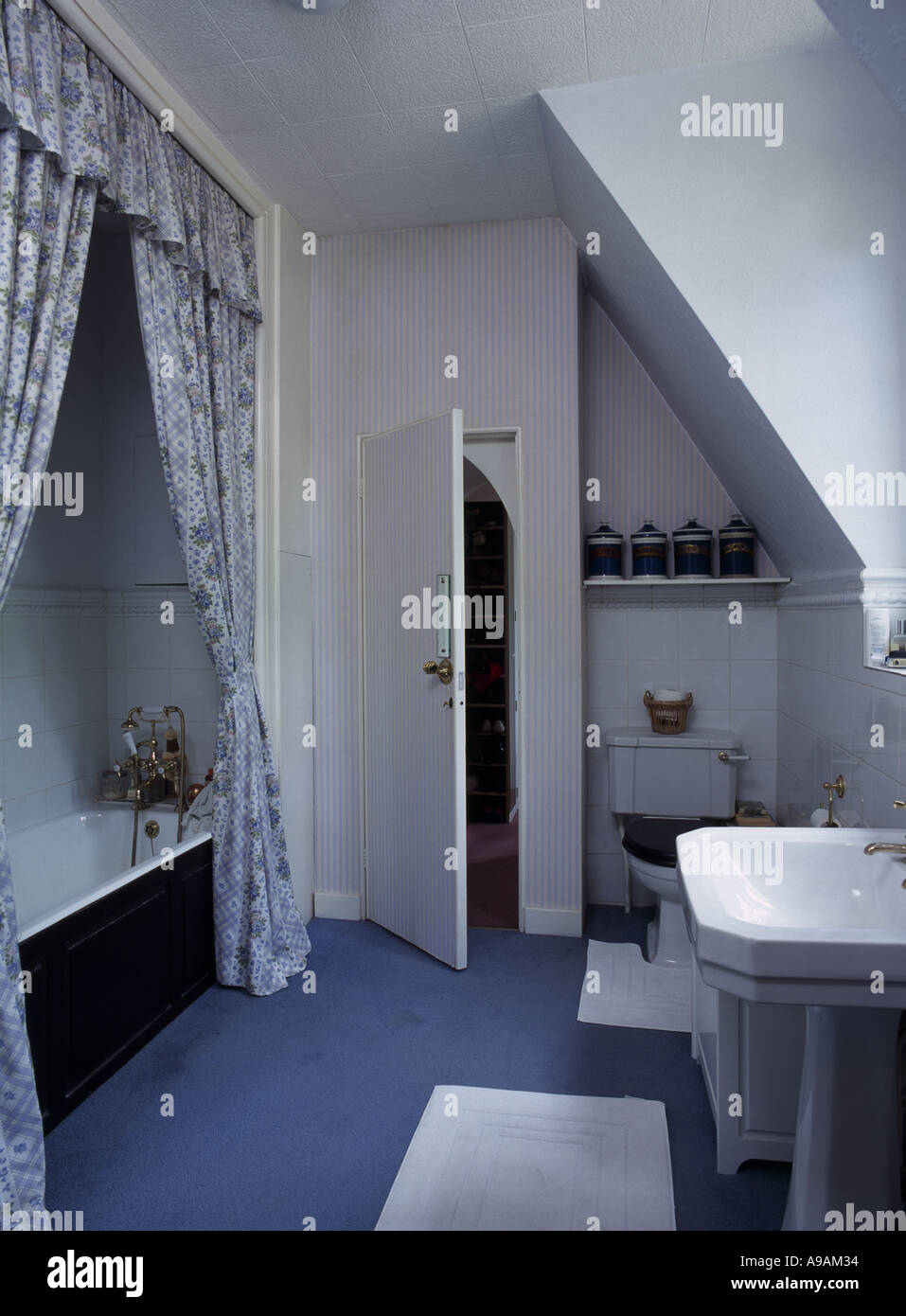 Des rideaux au-dessus de baignoire dans les petites salle de bains mansardée  avec tapis bleu Photo Stock - Alamy