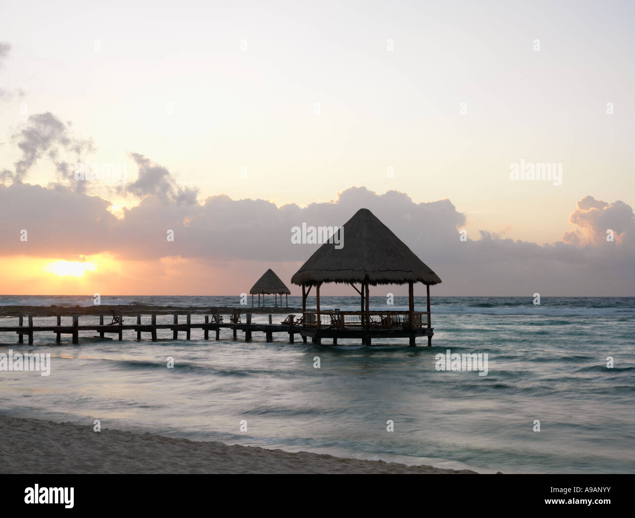 Le Mexique Péninsule du Yucatan Quintana Roo Cancun Riviera Maya pier avec palapa s'avance à l'eau de la plage au lever du soleil Banque D'Images