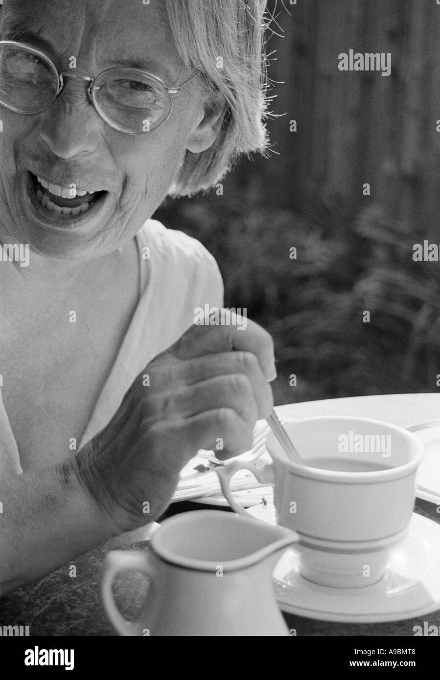 Femme plus rire, parler et boire le thé dans son jardin Banque D'Images