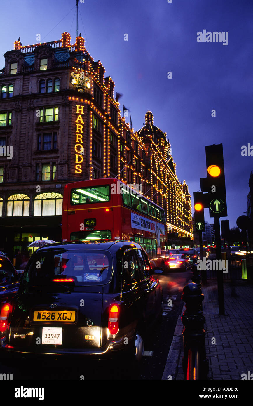 L'heure de pointe à l'extérieur de la célèbre grand magasin Harrods allumé jusqu'au crépuscule dans la ville de Londres Angleterre Royaume-uni Banque D'Images