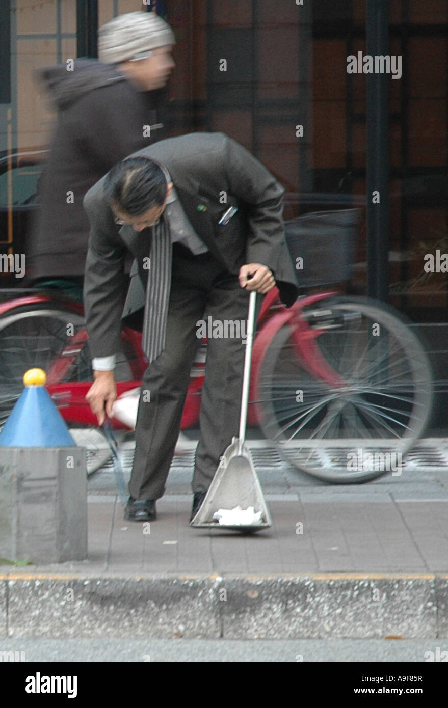 Un homme en costume ramasse les ordures dans la rue Banque D'Images
