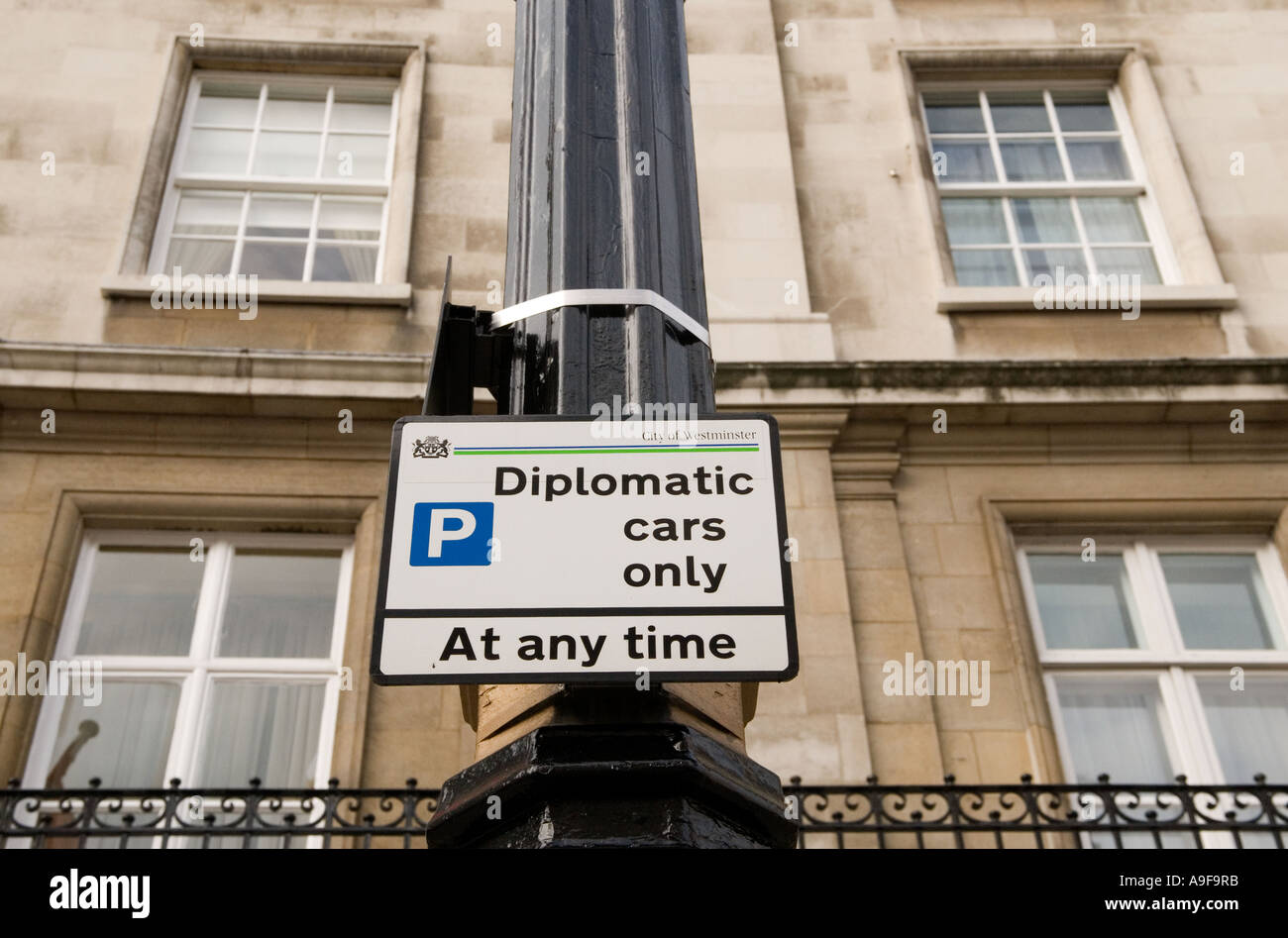 Un panneau fixé sur un lampadaire avise les conducteurs de voiture que seules les voitures diplomatiques sont autorisés à stationner ici à tout moment. Banque D'Images