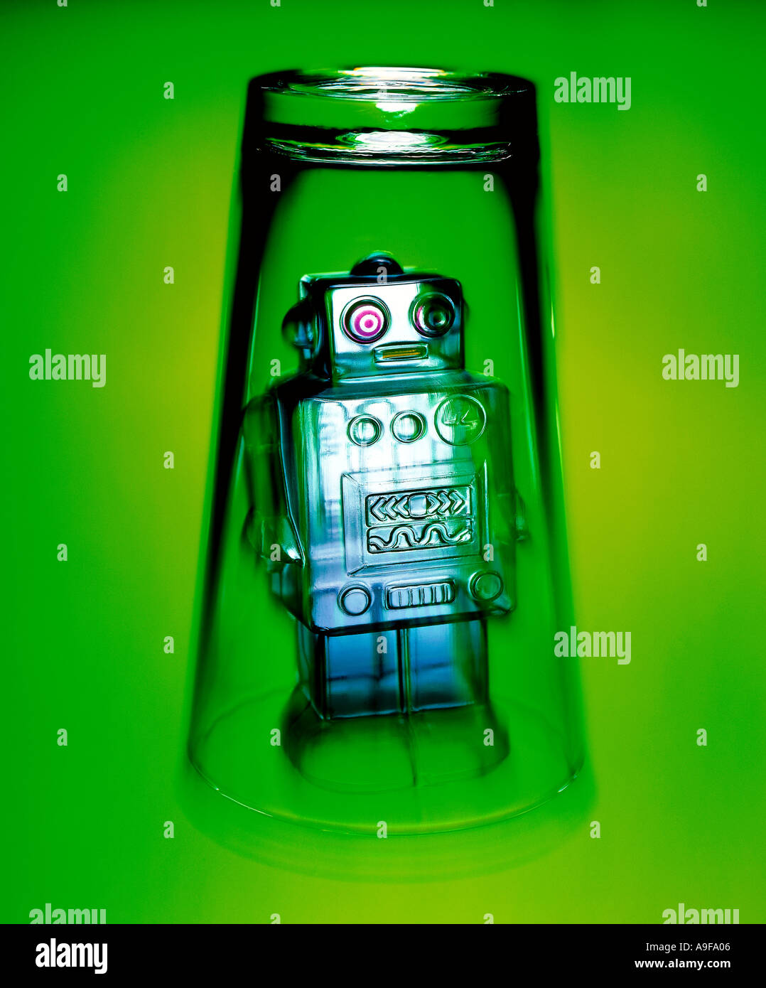 Robot jouet piégé dans le verre sur la surface verte Banque D'Images
