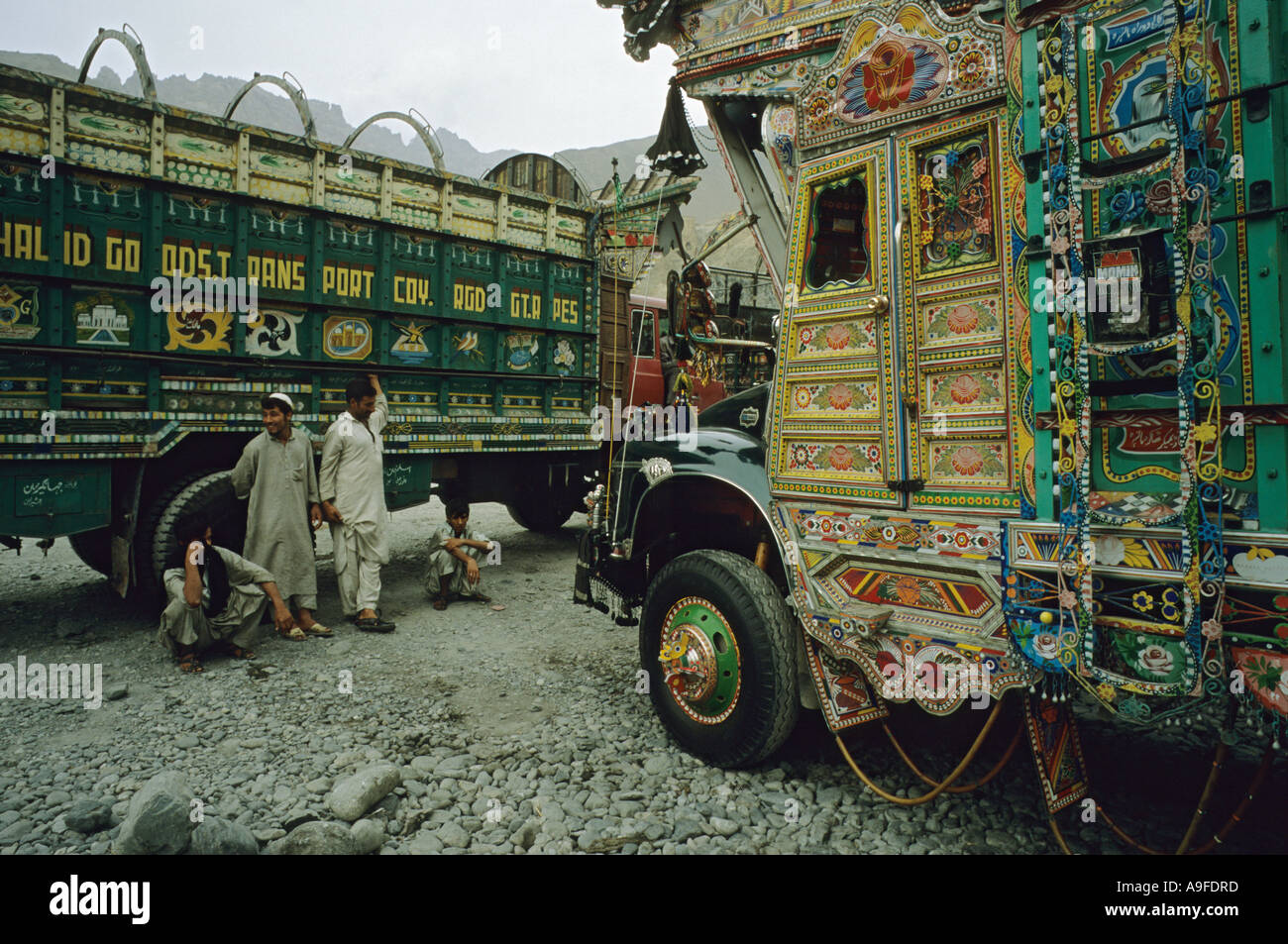 Trois hommes et garçon stand by coloré décoré des camions en ville de Sost Pakistan le frontière avec la Chine route Karakoram Banque D'Images
