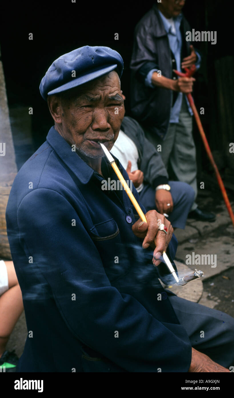 L'homme Chinois anciens fumeurs à l'aide de porte-cigarette, Kunming, Yunnan, Chine Banque D'Images
