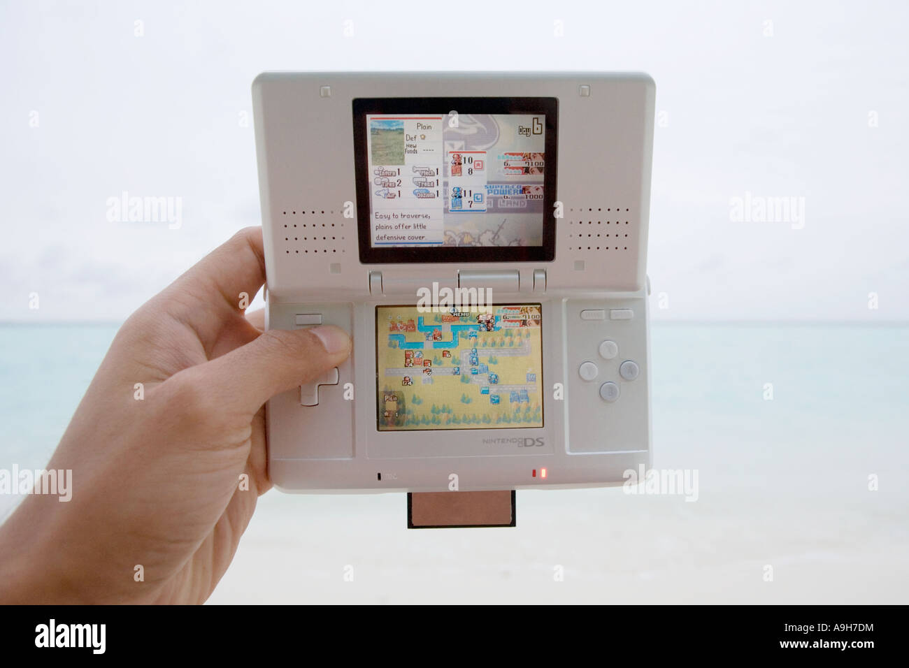 La lecture d'une Nintendo DS sur une plage tropicale Banque D'Images