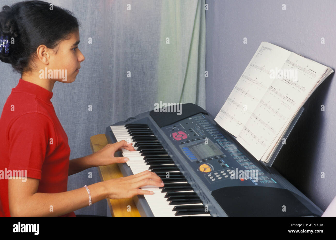 fille multiculturelle de 12 ans jouant au clavier électronique Banque D'Images
