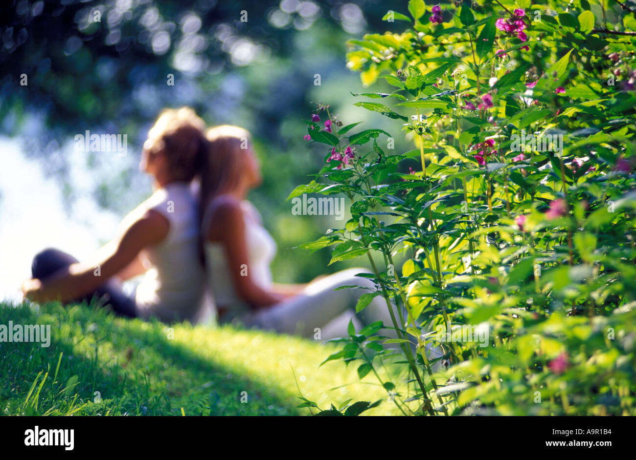 Les jeunes amoureux assis dos à dos sur chaude journée ensoleillée Banque D'Images