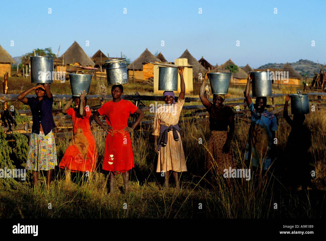Les jeunes femmes de porter des seaux d'eau dans les régions rurales du Zimbabwe village Banque D'Images