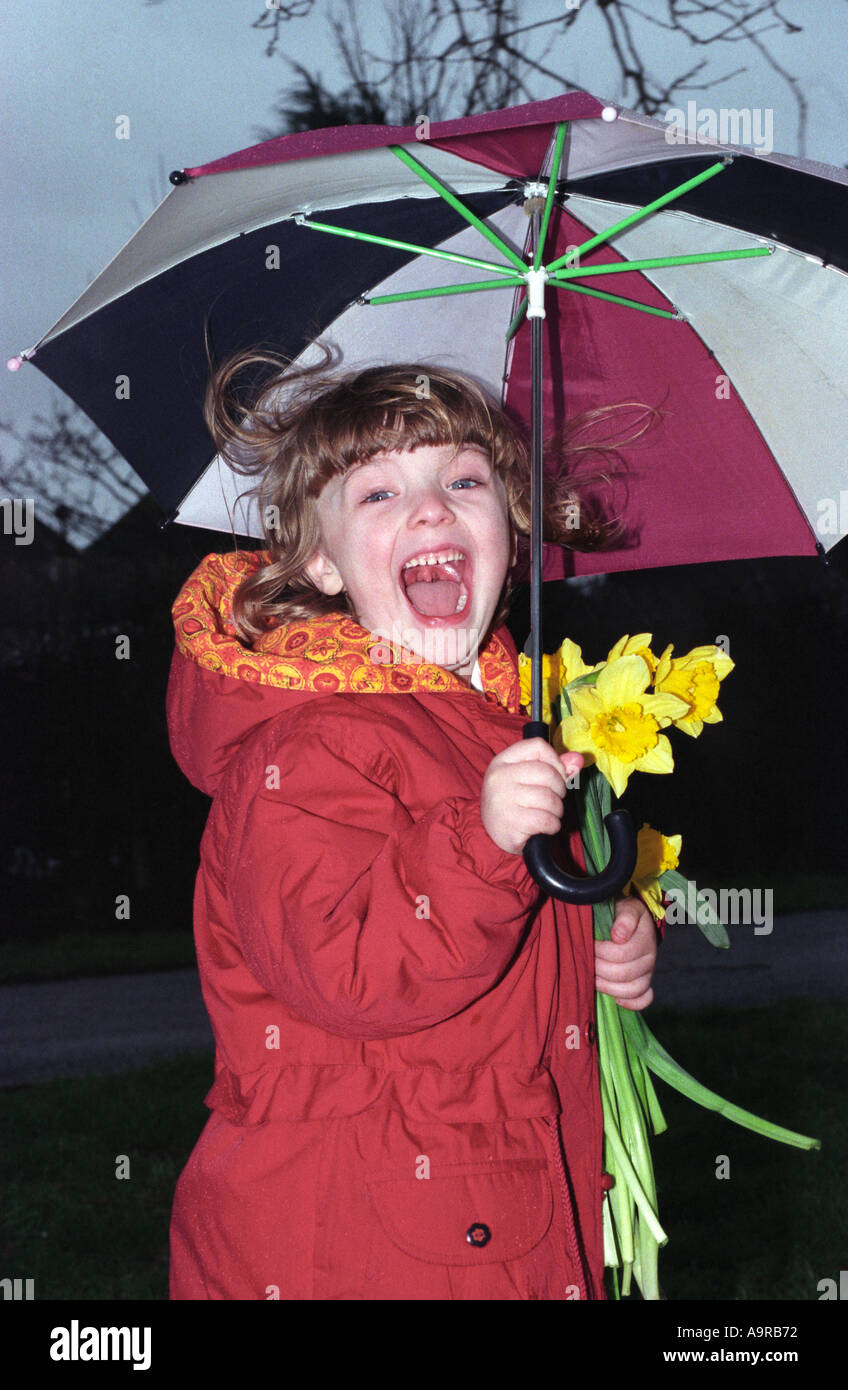 Jeune fille avec parapluie et bouquet de jonquilles, Middlesex, Royaume-Uni Banque D'Images