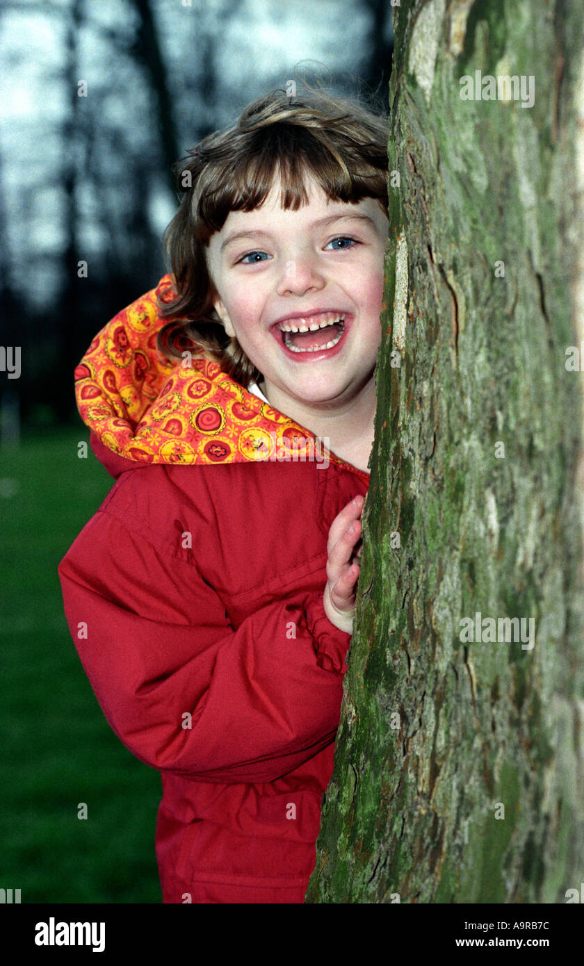Jeune fille sur le site de derrière arbre et smiling Middlesex UK Banque D'Images