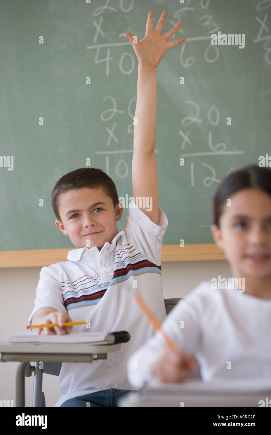 Boy raising hand in classroom Banque D'Images