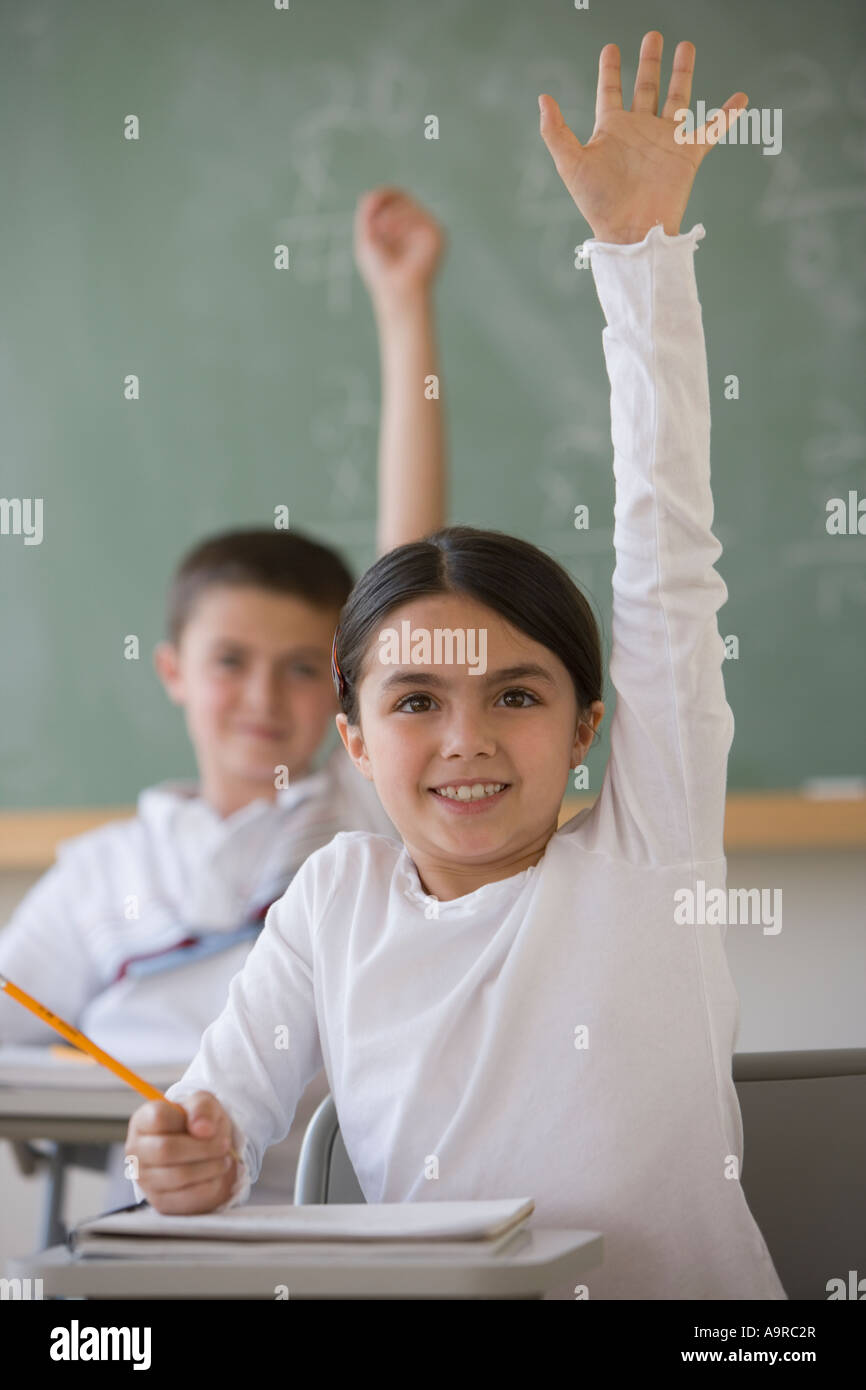 Girl raising hand in classroom Banque D'Images