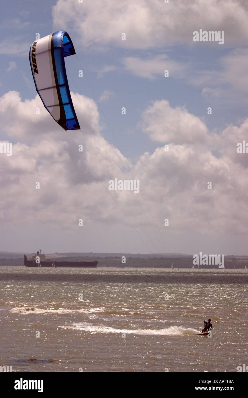 Un kitesurfeur serpents son chemin sur le Solent et l'île de Wight et un grand navire commercial à l'arrière-plan Banque D'Images