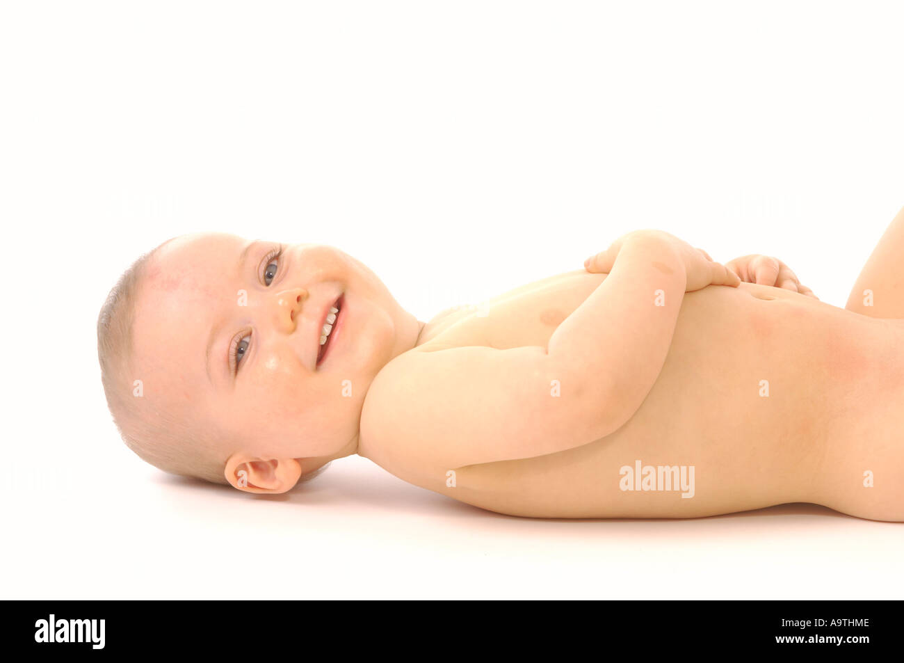 Bébé caucasien sans couche allongé sur le dos souriant à la caméra. Vu sur fond blanc. Banque D'Images Bébé caucasien sans couche allongé sur le dos souriant à la caméra. Vu sur fond blanc. Banque D'Images