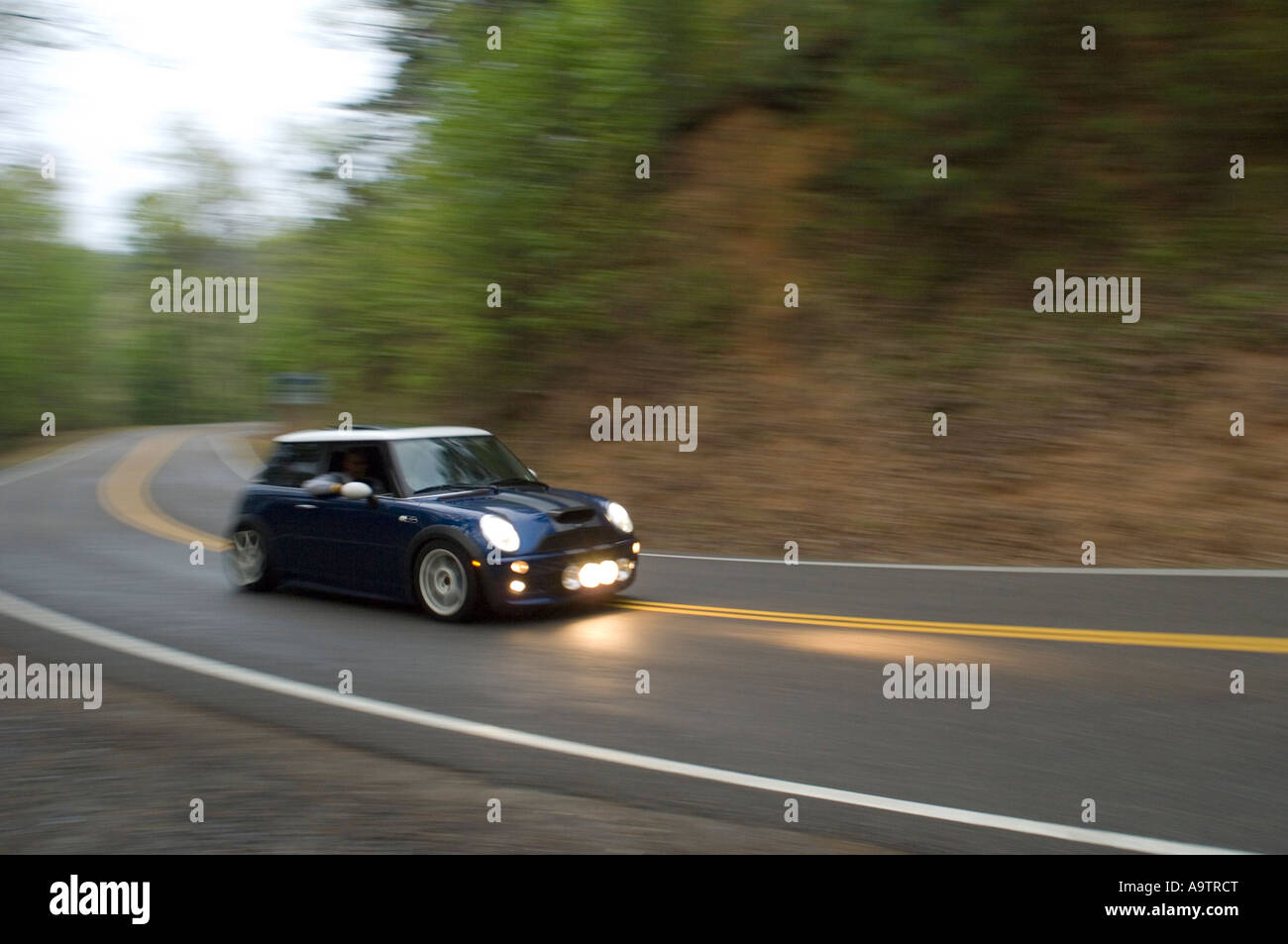 MINI Cooper S la conduite sur une route rurale de bobinage au crépuscule Banque D'Images