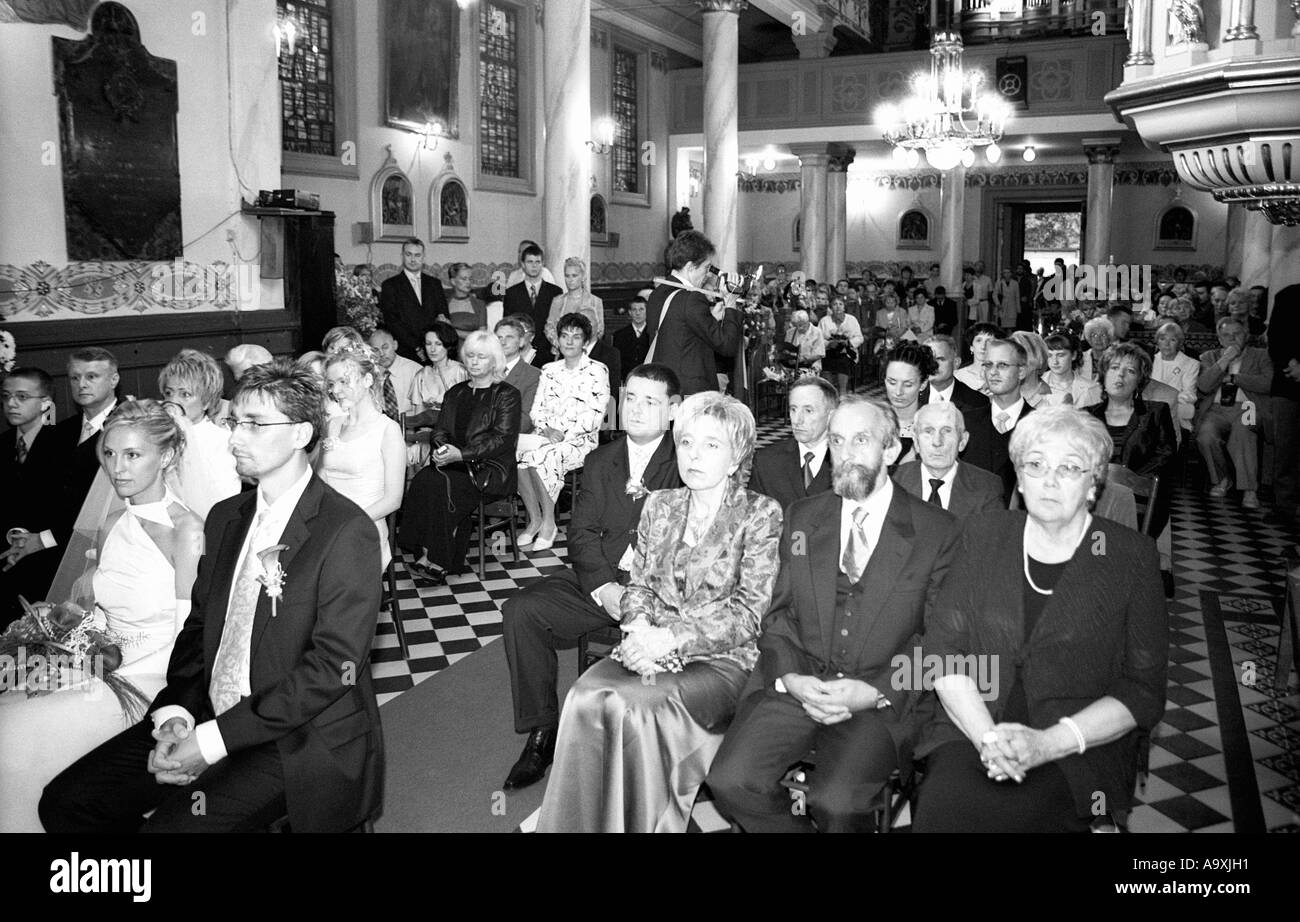 Pologne, Lodz, mariée et le marié avec les invités assis à l'église (B&W) Banque D'Images
