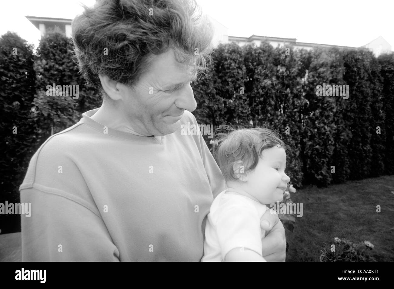 La Pologne, senior man holding granddaughter (6-9 mois) dans le jardin (B&W) Banque D'Images