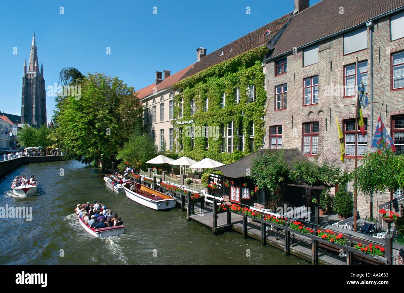 Bruges, Belgique. Voyage en bateau sur un canal dans le centre de la vieille ville avec Onze Lieve Vrouwekerk derrière. Banque D'Images