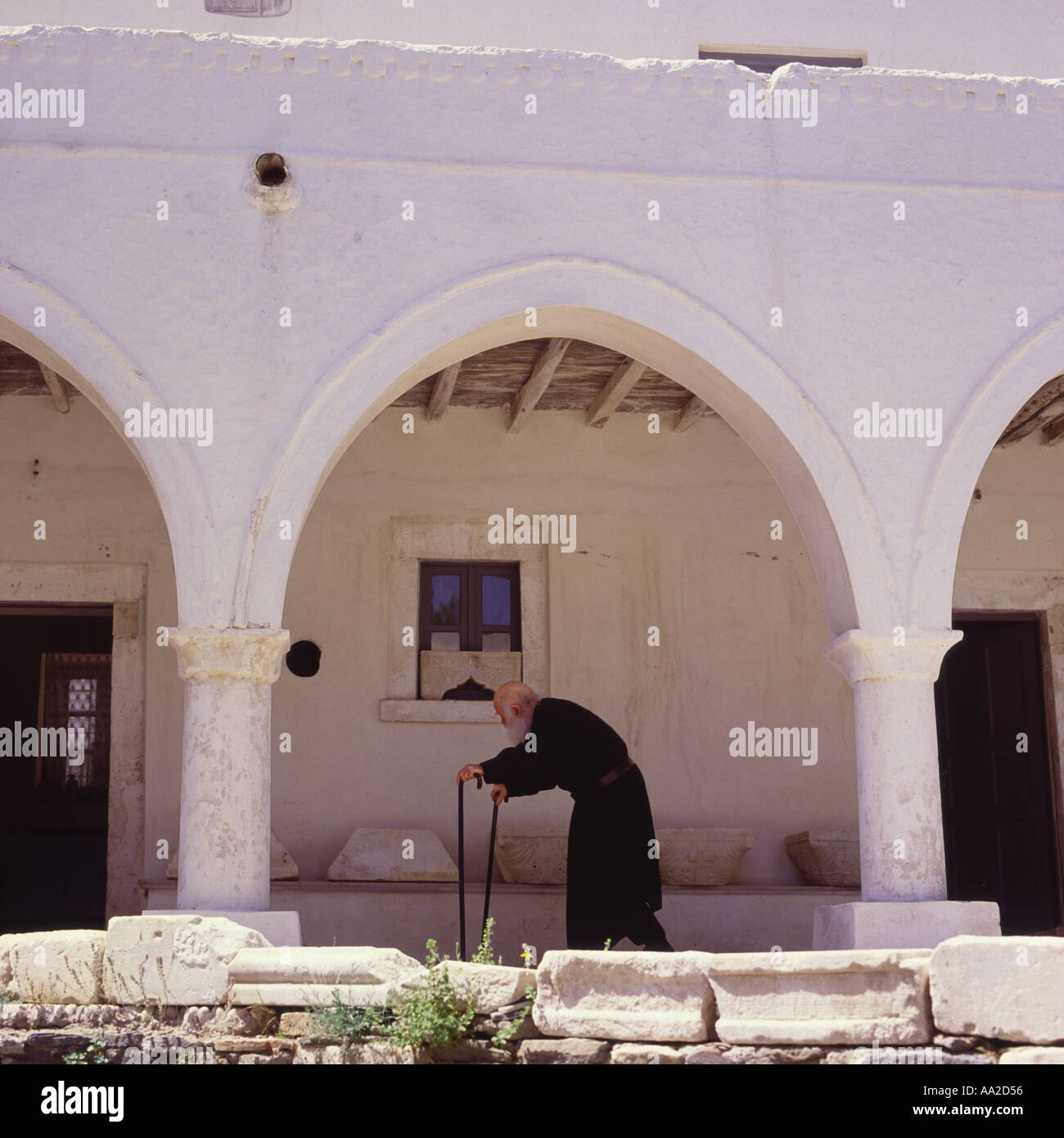 Un vieux prêtre promenades à travers les arcades et les cloîtres de l'Église Ekatontapiliani à Parikia, sur l'île de Paros dans les îles Grecques Banque D'Images