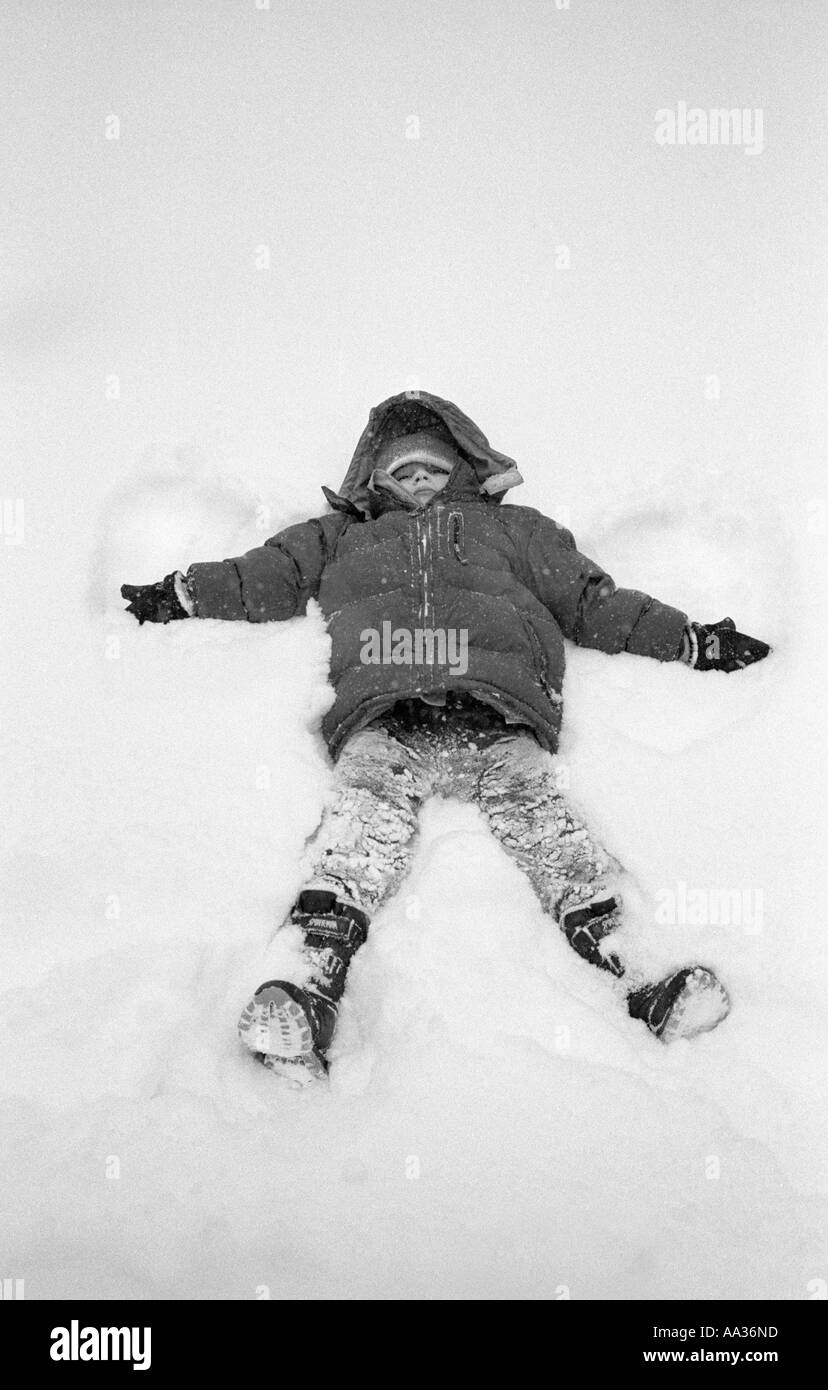 Petit garçon faisant des anges dans la neige dans la neige Banque D'Images