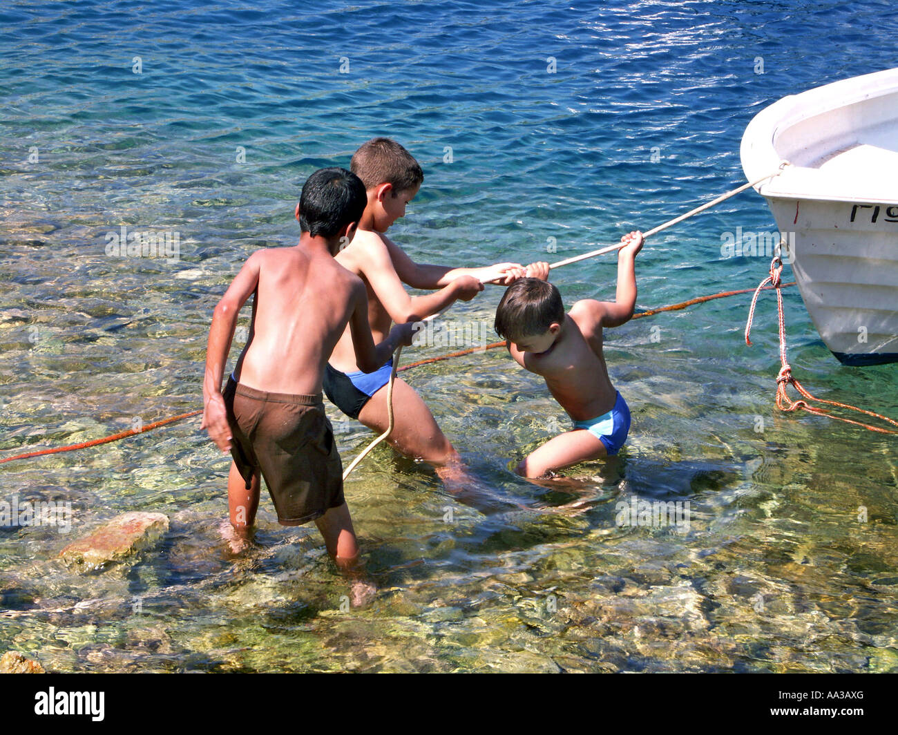 Les garçons grecs tirant voile à Symi, Dodécanèse, Grèce. Banque D'Images