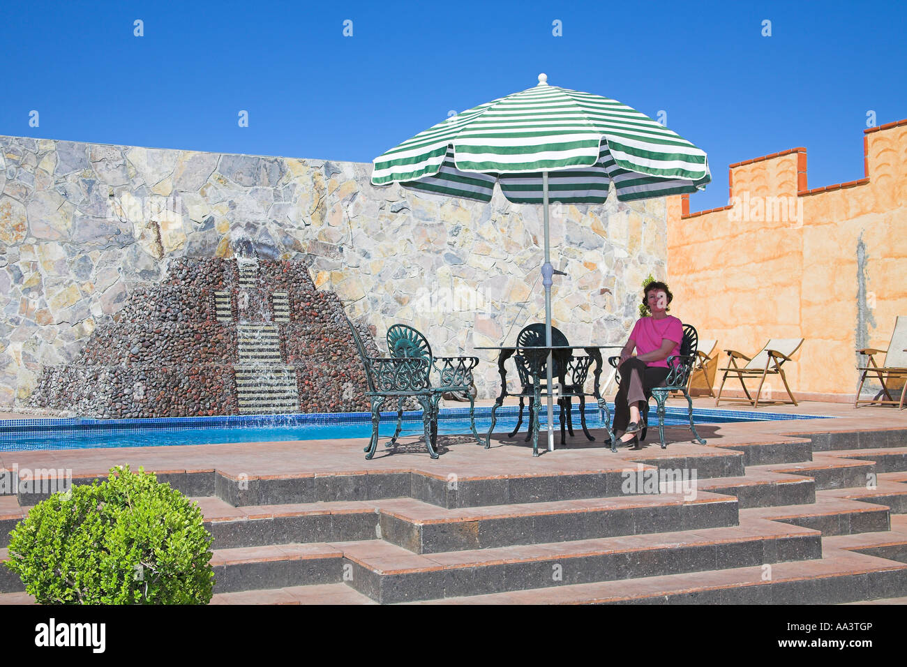 Assis sous un parasol à côté de tourisme piscine, Teotihuacan, Mexico, Mexique Banque D'Images